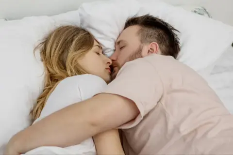 Para młodych ludzi śpi przytulona, ich twarze blisko siebie. Czy to sen, czy może spełnienie erotycznych marzeń?