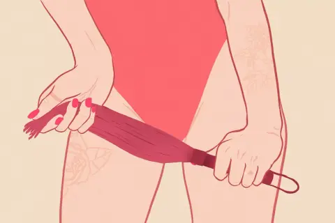 Dłoń trzymająca biczyk, sugerująca eksplorację tego, co to jest BDSM. Tatuaże na skórze.